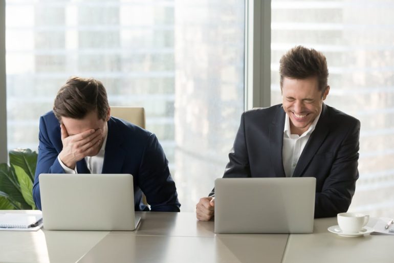 two laughing men sat at computers