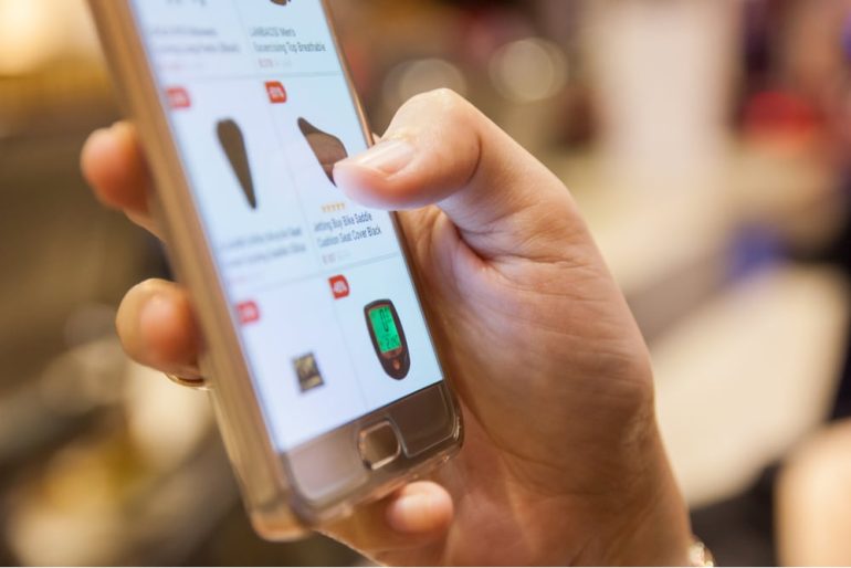 close up of hands holding a smartphone scrolling through an ecommerce product page